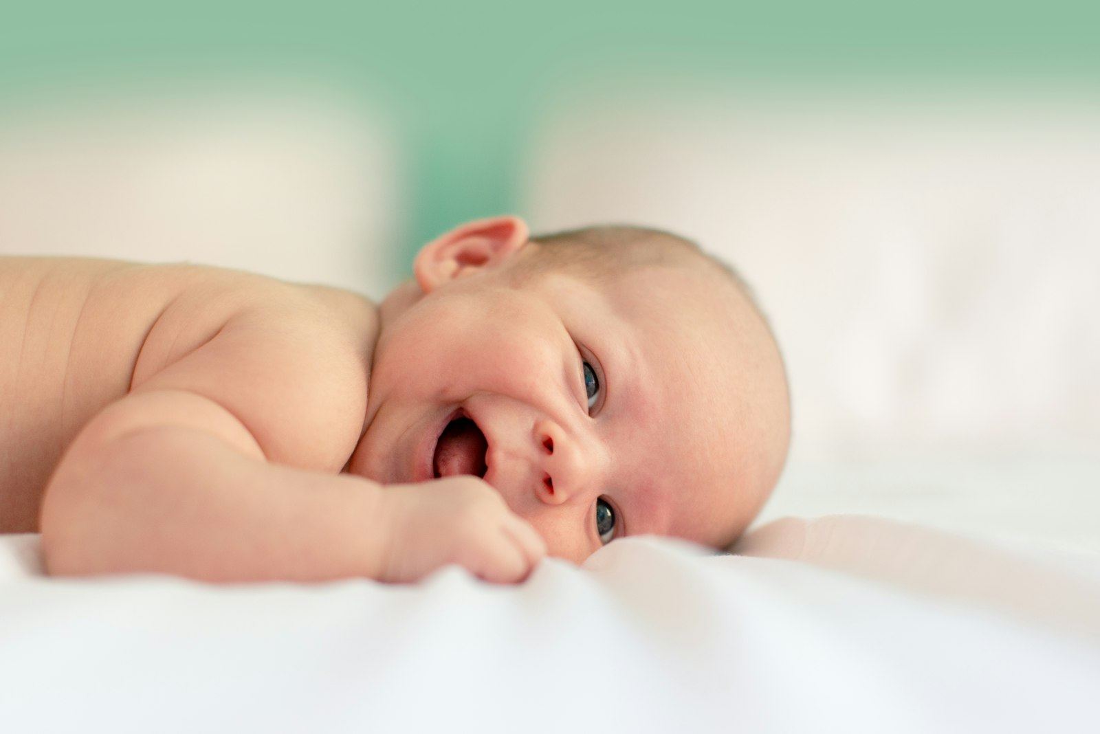 Smiling newborn lying on a soft white cloth