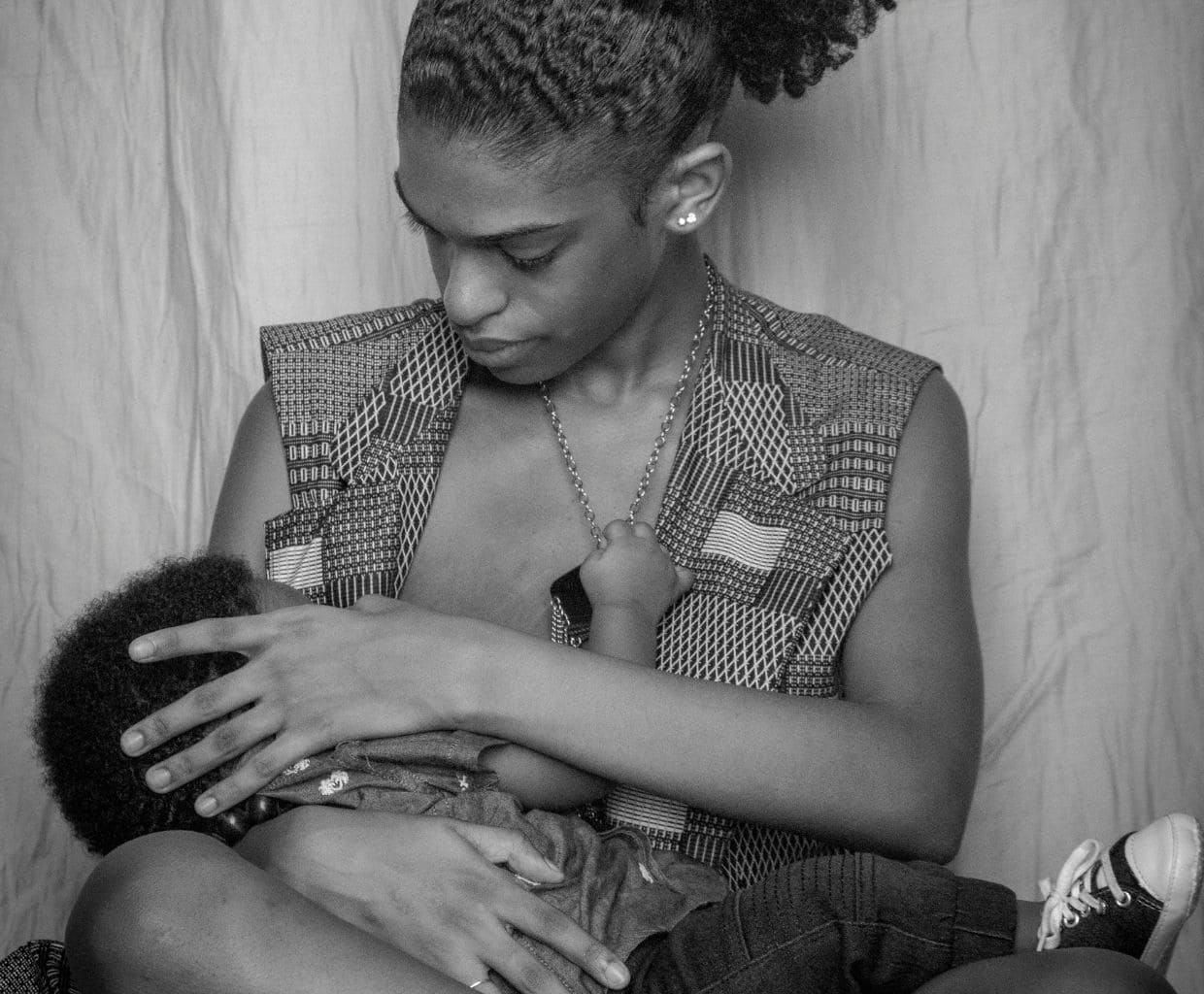 Black-and-white photo of a mother looking down at the toddler she is breastfeeding